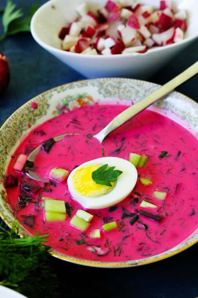 Closeup of cold red beet soup served with a boiled egg
