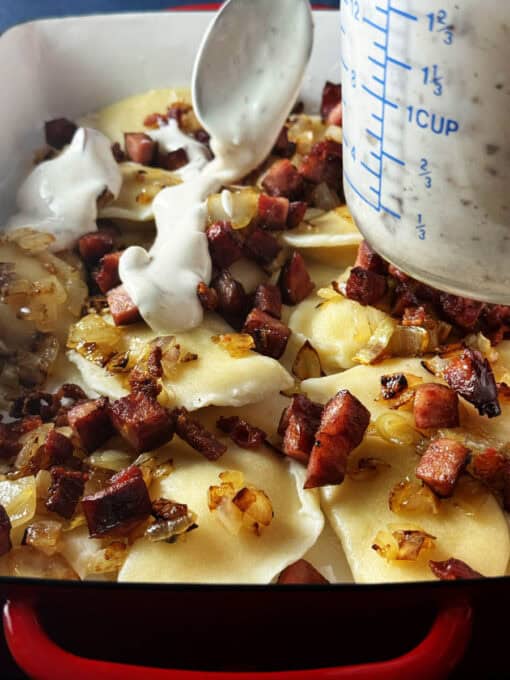 Sauce is being poured over the pierogi