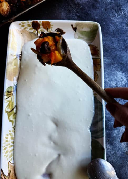 Fall roasted vegetables being placed on the whipped feta