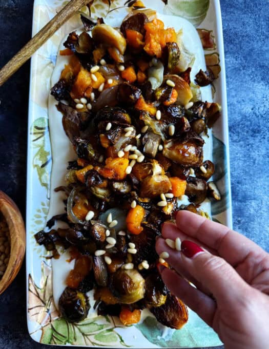 Garnishing fall roasted vegetables with pinenuts