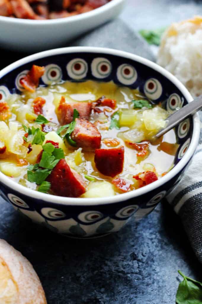 Close up of a bowl of sauerkraut soup with bacon and kielbasa